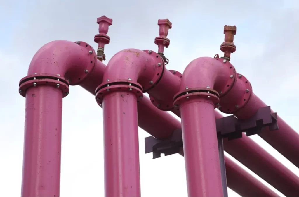 Three pink pipelines with valves in a structured arrangement.
