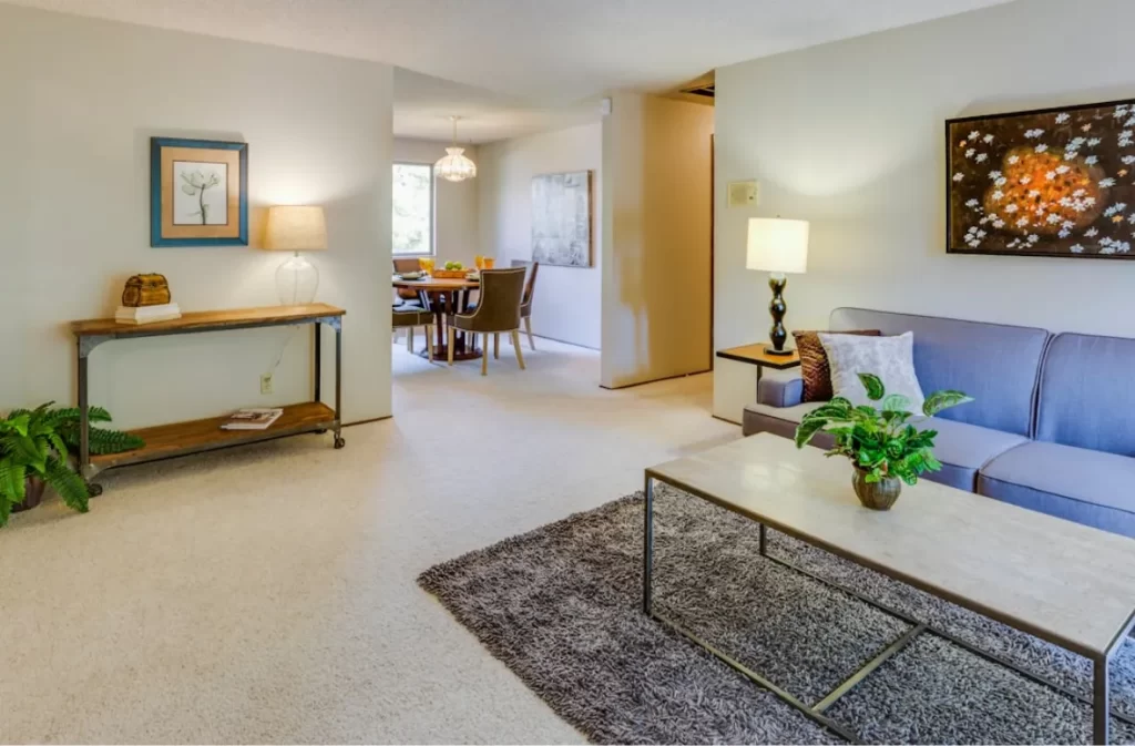 Staged living area with neutral decor and a garden view.