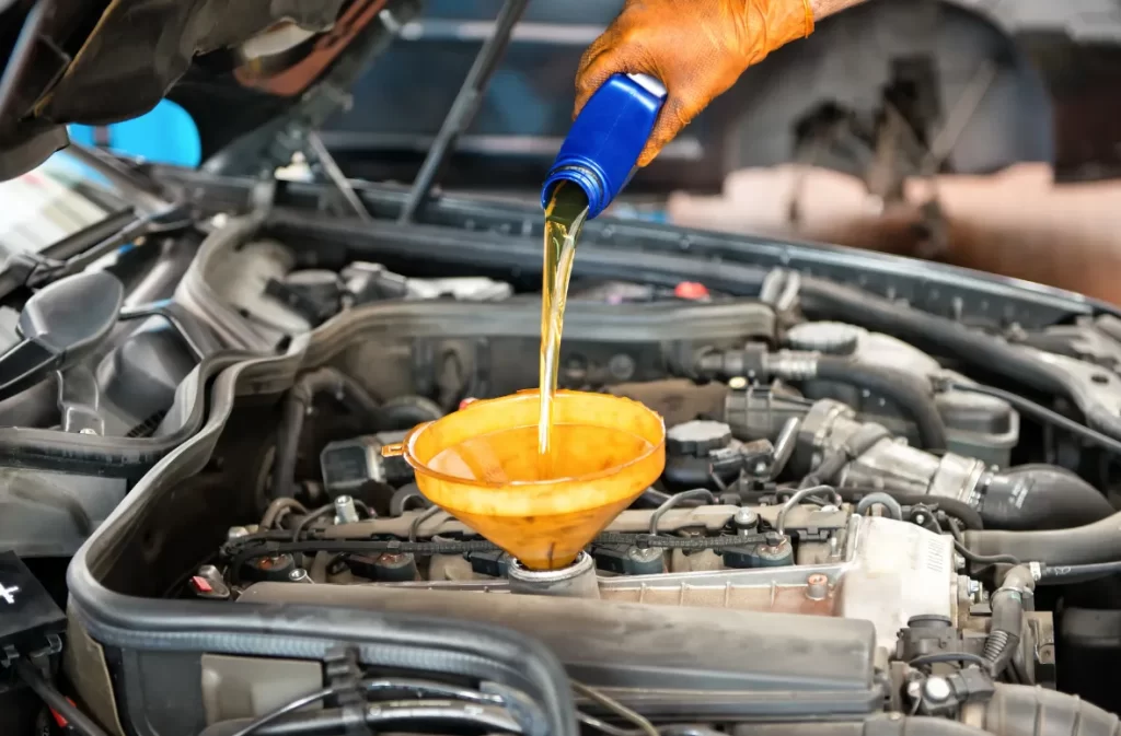 Oil being poured into a car engine with a funnel.